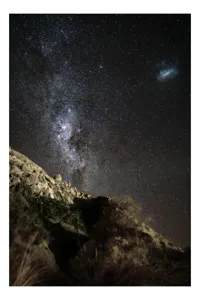 Tablou Canvas, "Calea Lactee deasupra stâncilor iluminată", Stele, Cer, Roci, Univers, Noapte, Peisaj, Galaxie, Mister, Natură, Lumină, 100 x 150 cm