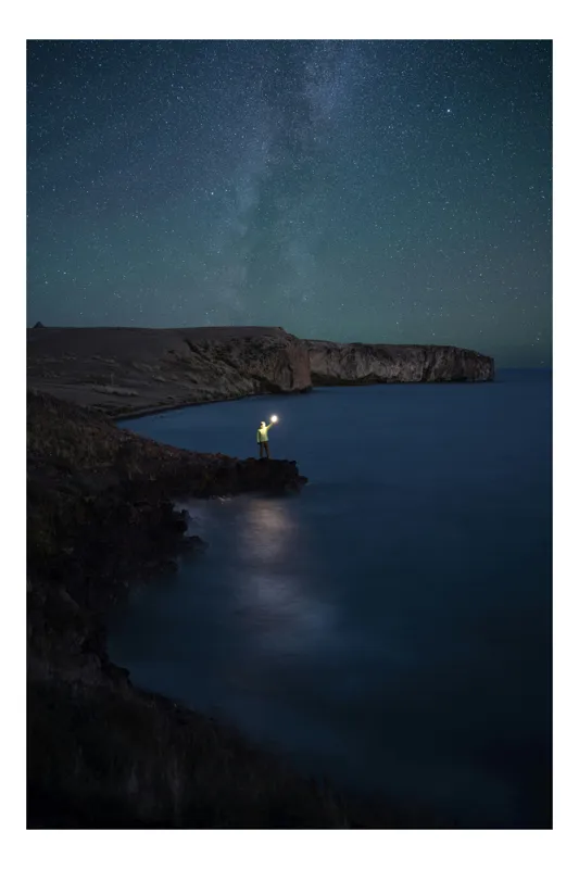 Tablou Canvas, "Omul și lumina sub stele", Stele, Mare, Noapte, Lumină, Țărm, Stâncă, Cer, Singurătate, Reflexie, Orizont, 100 x 100 cm