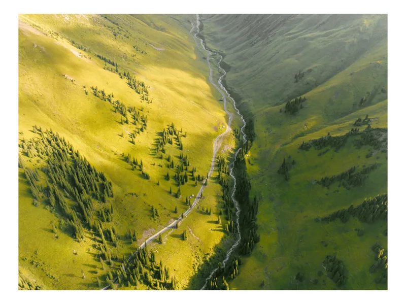Tablou Canvas, "Valea îmbrățișată de soare și pârâu", Văi, Râu, Verdeață, Pini, Lumină, Munți, Peisaj, Natură., 70 x 50 cm