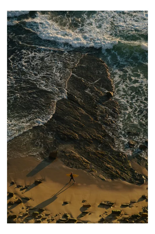 Tablou Canvas, "Surfer singur pe țărmul stâncos", Valuri, Stânci, Plajă, Apus, Surfer, Umbre, Ocean, Nisip, Texturi, Natură, 26 x 39 cm