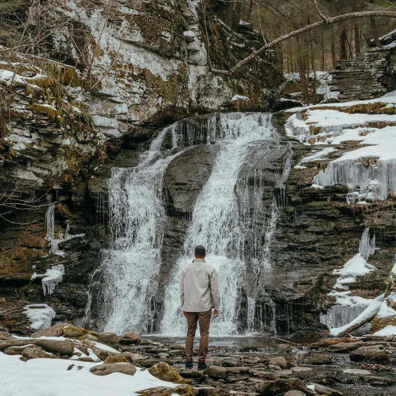 Tablou Canvas, "Om admira cascada înzăpezită iarna", Cascadă, Zăpadă, Gheață, Pădure, Roci, Figură Umană, Iarnă, Natură, Tranquilitate, Aventură, 50 x 50 cm – poza 2
