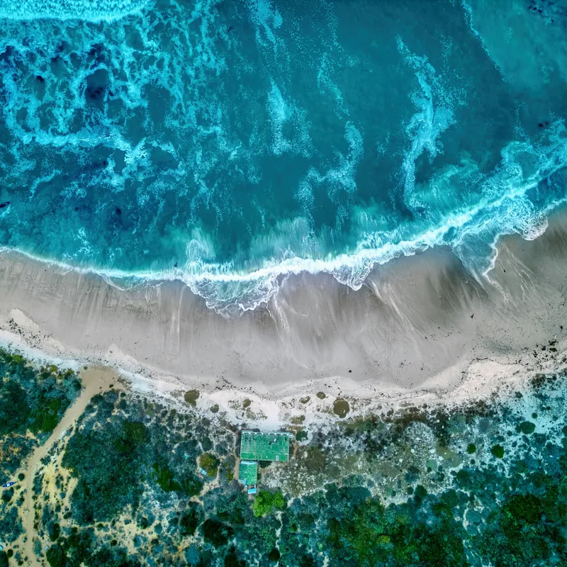 Tablou Canvas, "Valurile albastre la țărmul nisipului", Ocean, Valuri, Plajă, Nisip, Vegetație, Albastru, Argintiu, Natură, Aerian, Peisaj, 100 x 100 cm – poza 2